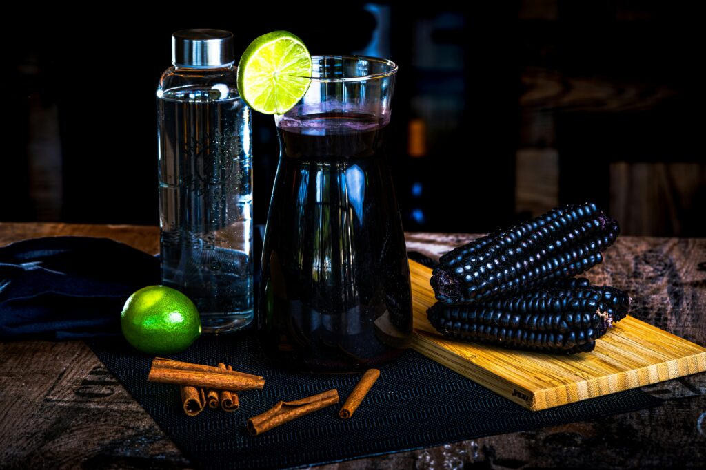 Chicha Morada drink with purple corn, cinnamon, and lime on a rustic table setting.